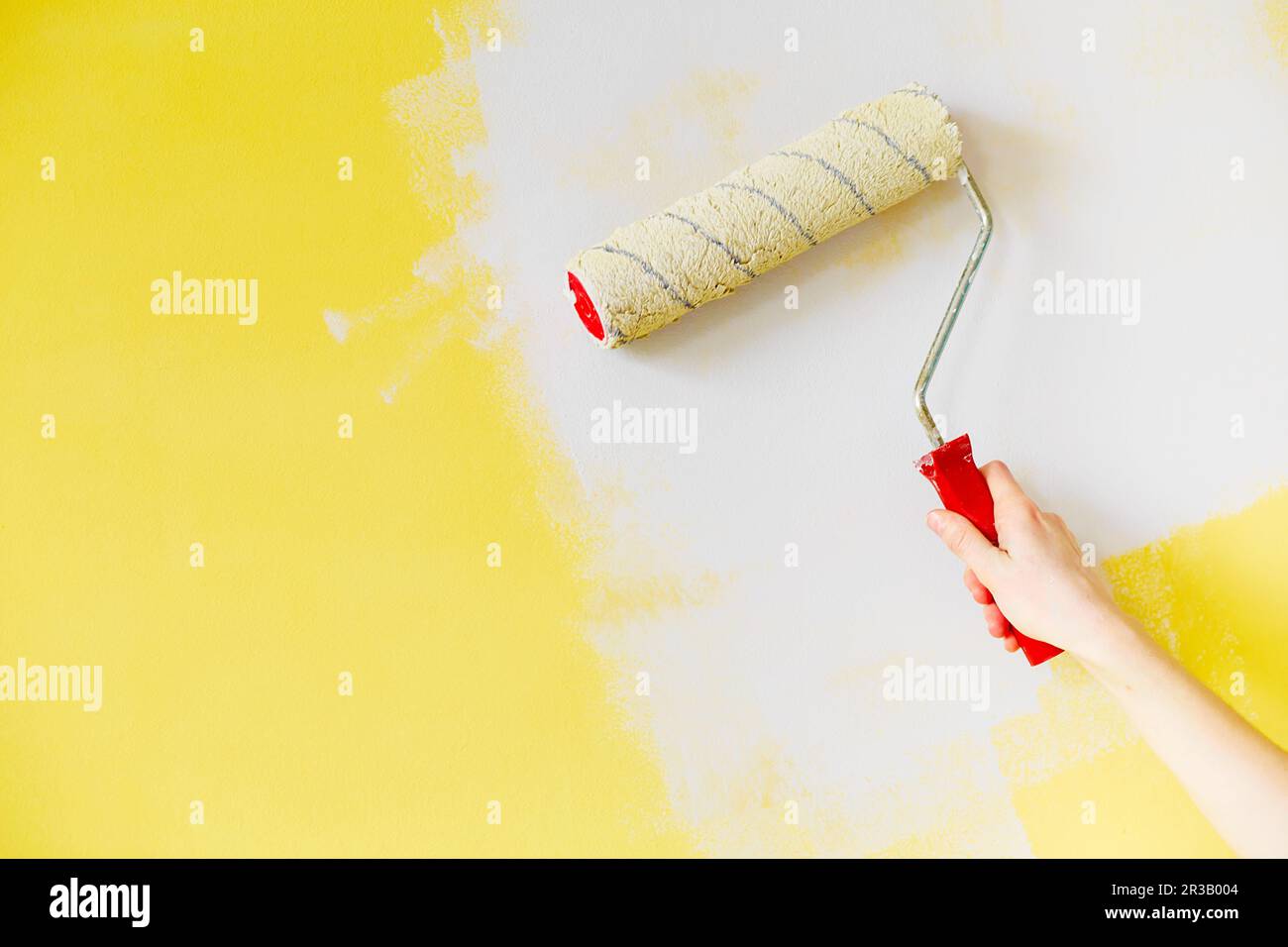 Female hand painting wall with paint roller. Close up of Decorator's