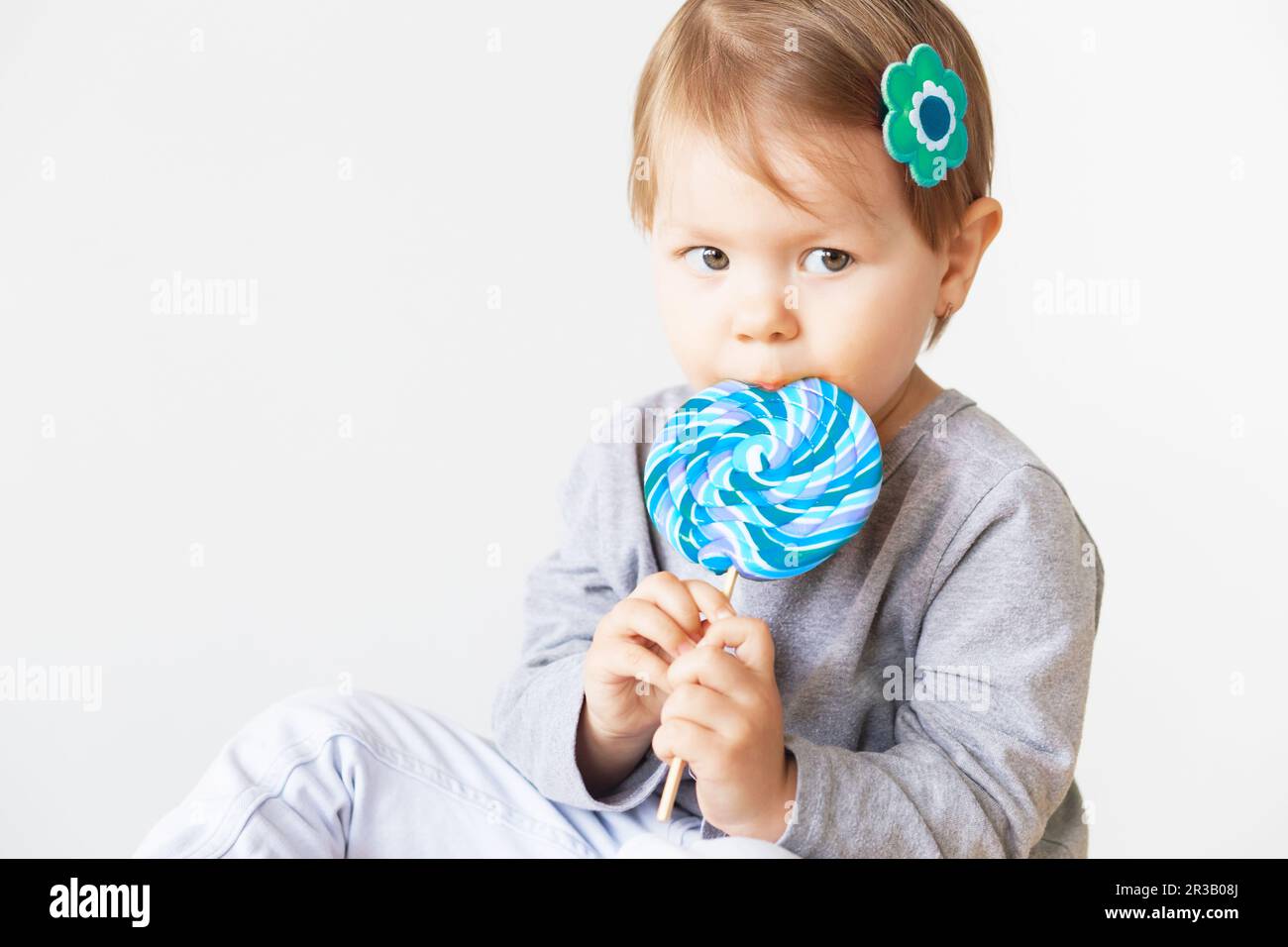 Small girl eating lollipop. Happy children with a big delicious candy