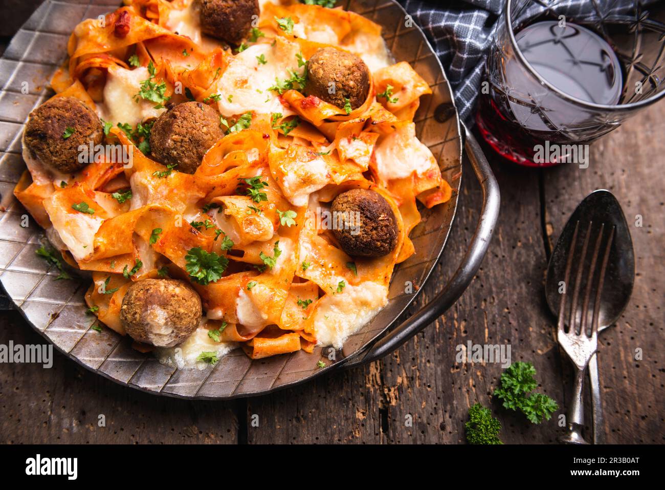 Gratinated tagliatelle with chickpea balls, tomato sauce and almond cheese Stock Photo