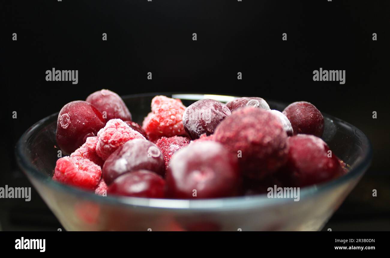Side View Of Frozen Cherry And Raspberry Fruits In A Bowl Over Black ...