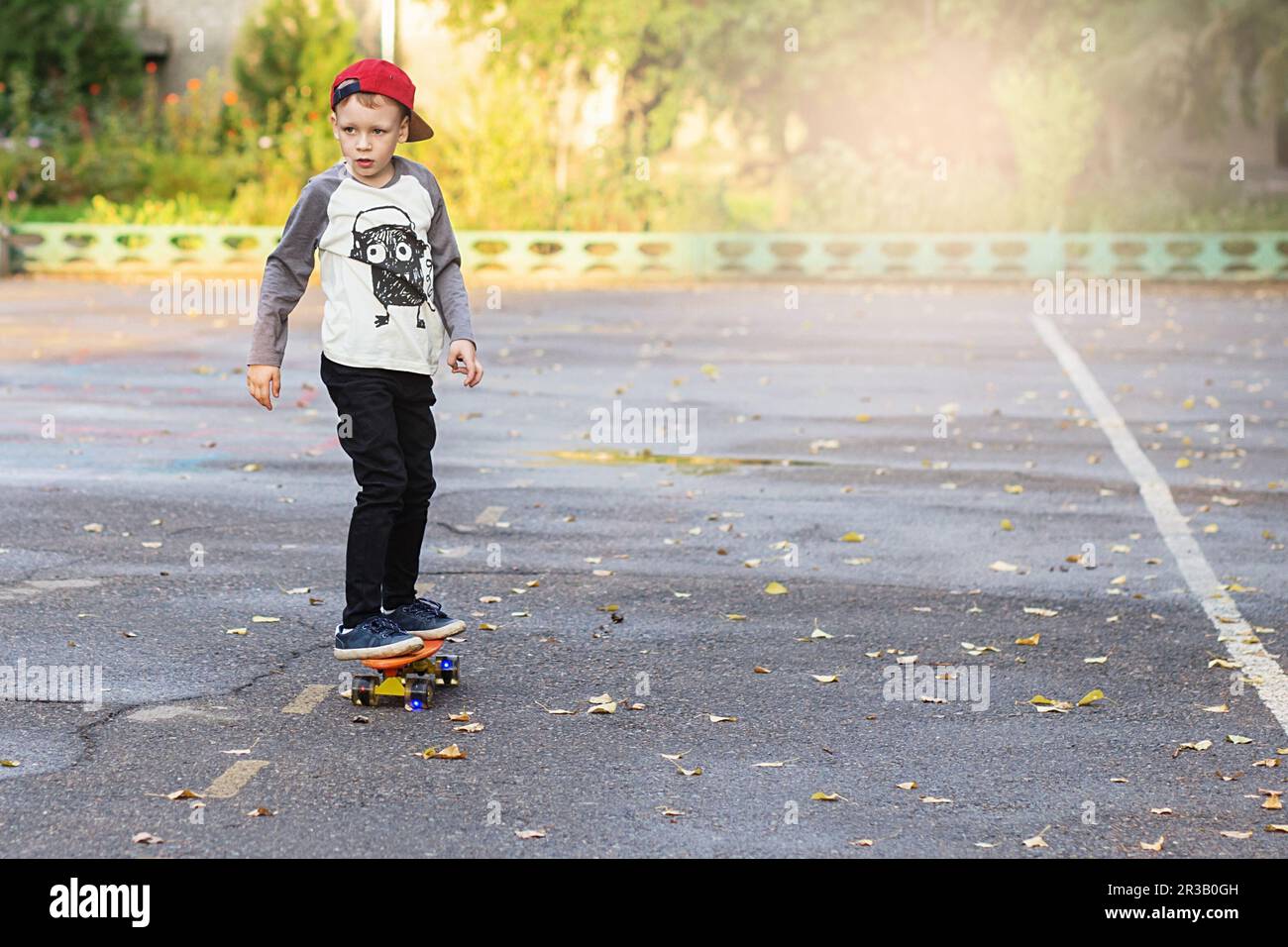 Little urban boy with a penny skateboard. Young kid riding in the park ...