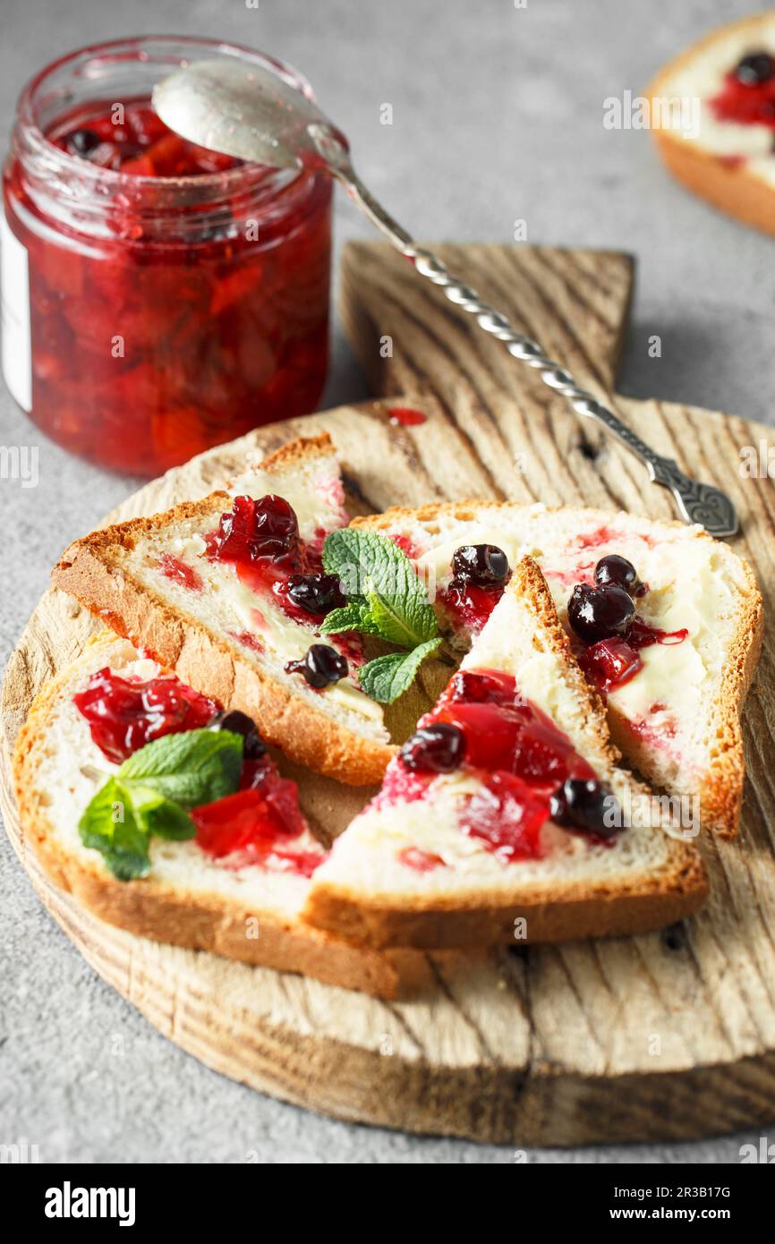 Grapefruit marmalade with berry platter. Jar of blood orange jam with silver spoon and sandwiches on Stock Photo