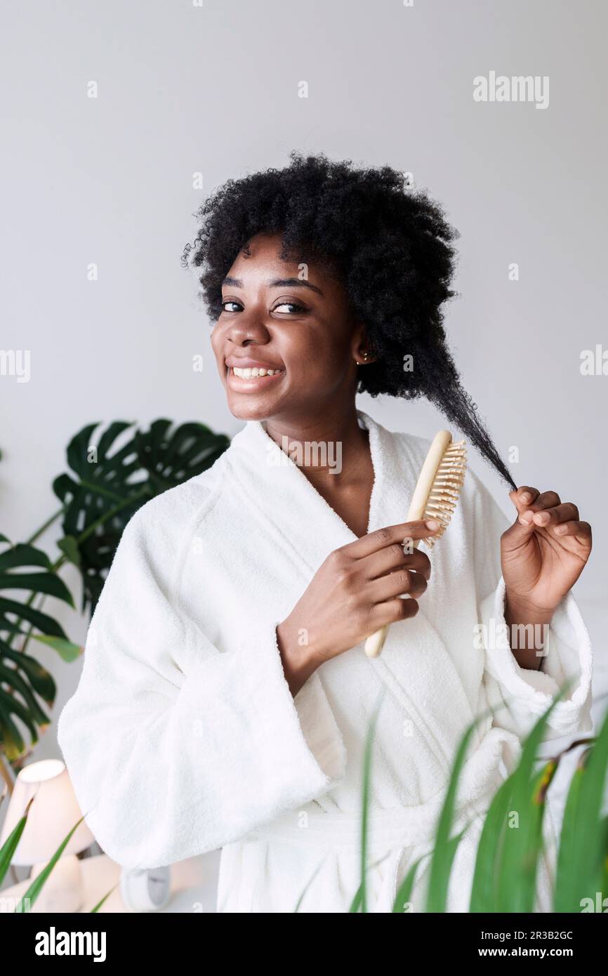 Happy Young Woman Combing Hair At Home Stock Photo - Alamy