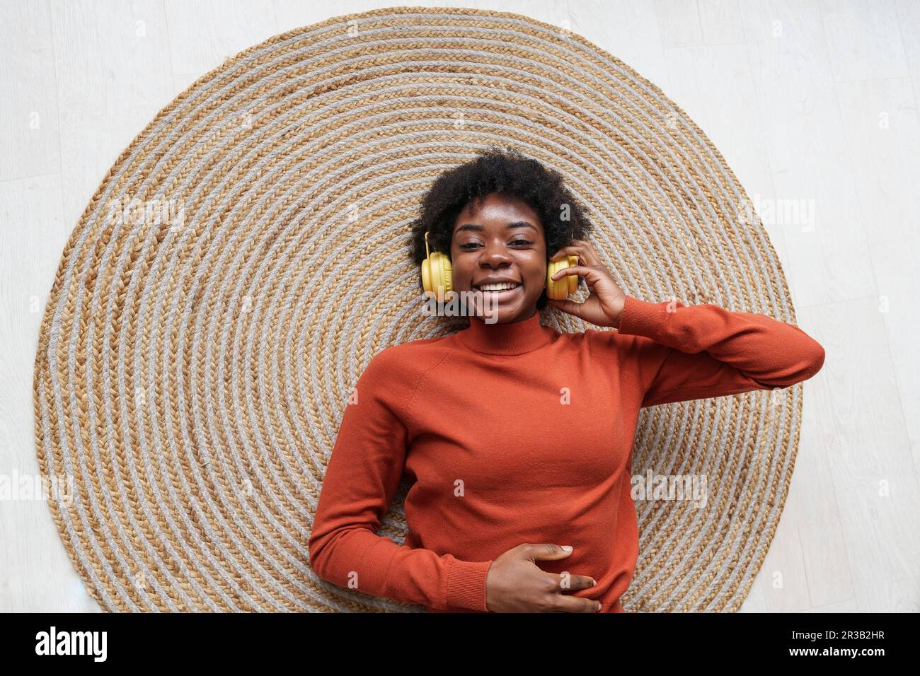 Happy young woman lying on rug and listening to music Stock Photo - Alamy