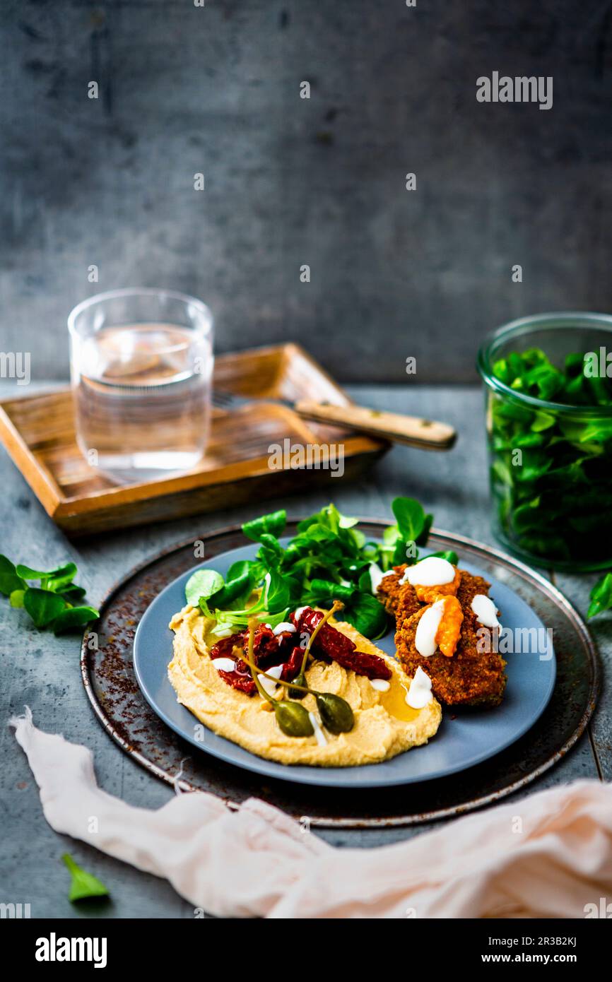 Falafel with hummus, lamb's lettuce, dried tomatoes and capers Stock Photo