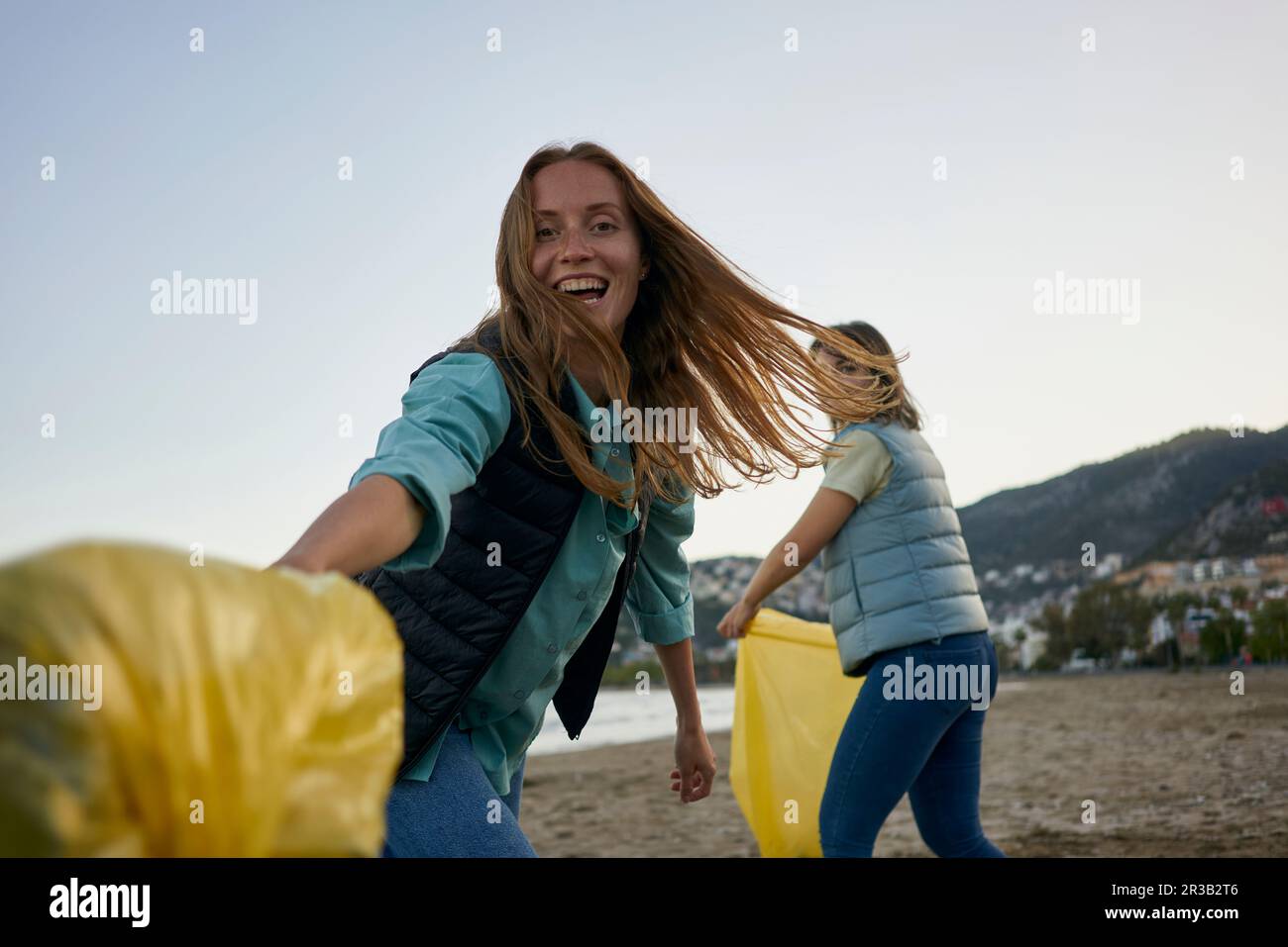 Cheerful volunteers having fun holding garbage bags at beach Stock Photo