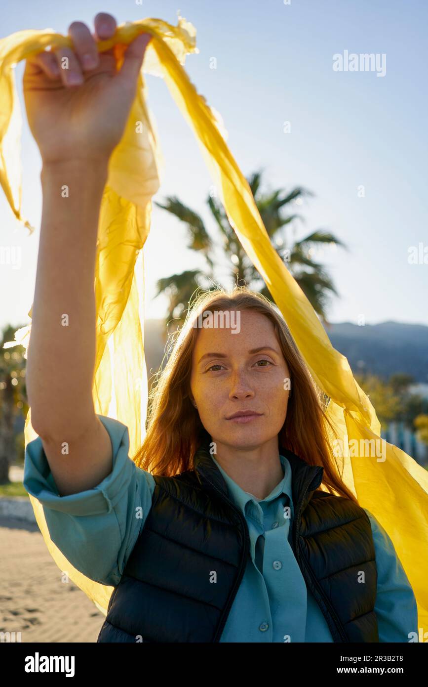 Volunteer holding yellow plastic bag at beach Stock Photo Alamy