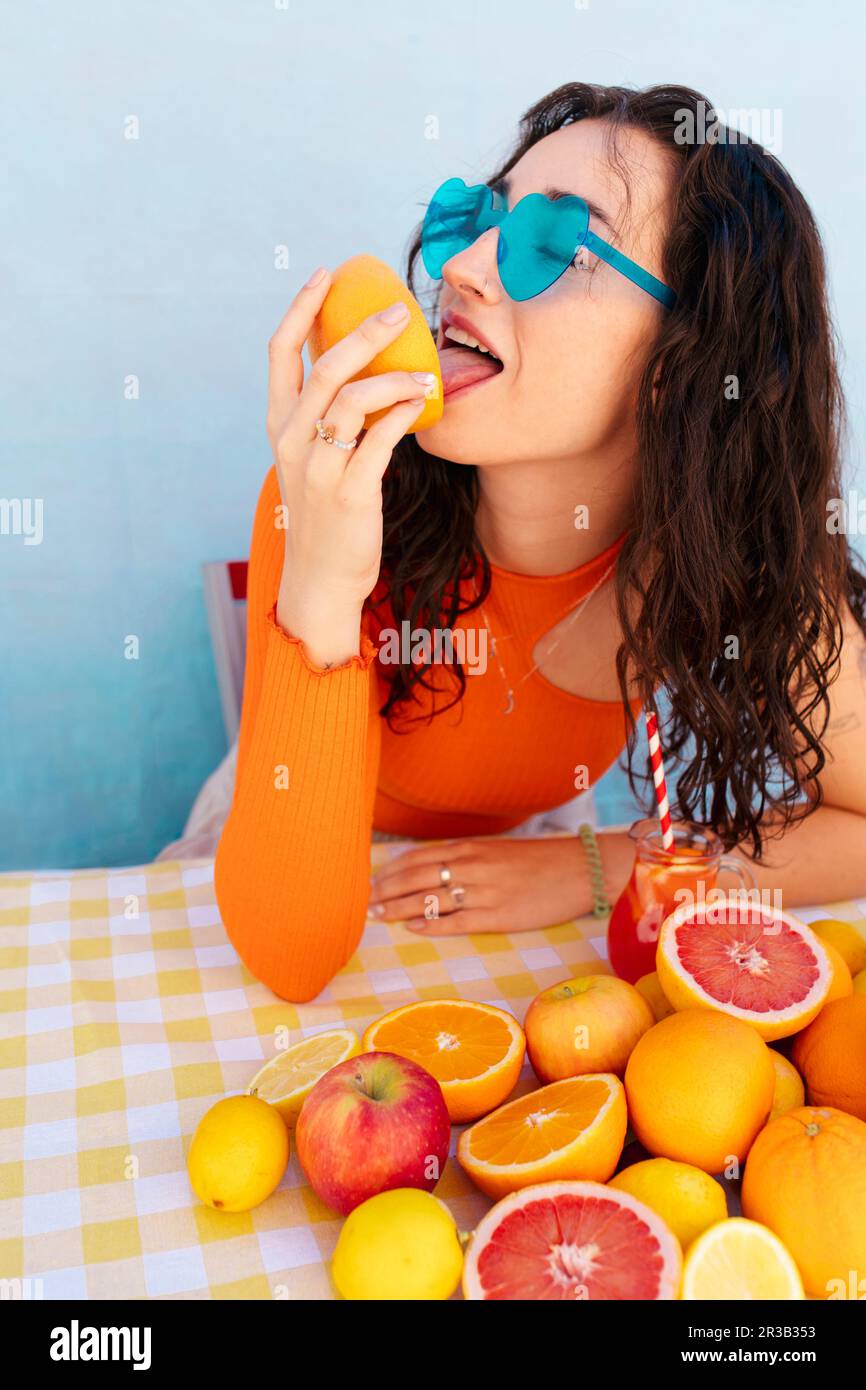 Woman wearing sunglasses licking citrus fruit Stock Photo