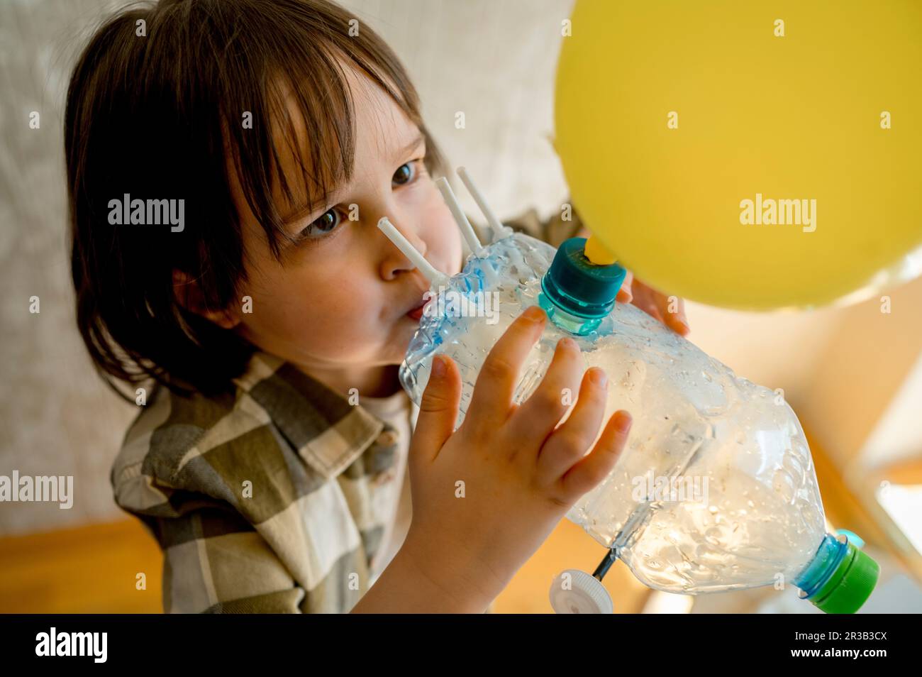 Boy blowing balloon through plastic bottle car at home Stock Photo - Alamy