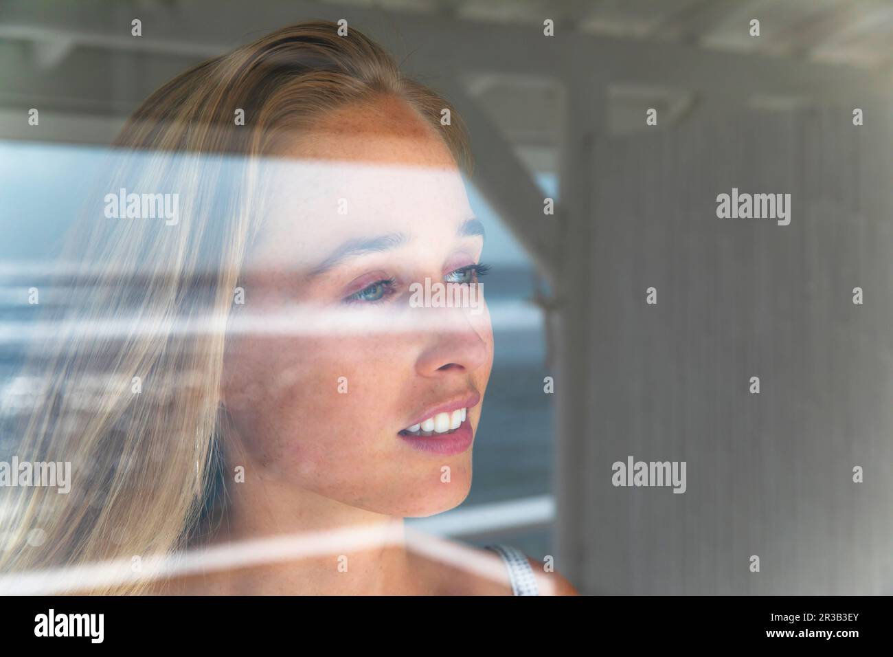 Thoughtful young woman looking through window Stock Photo