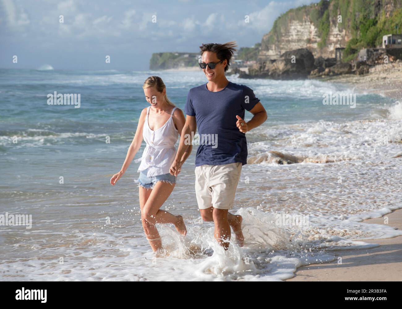 Happy young couple running in sea water at beach Stock Photo