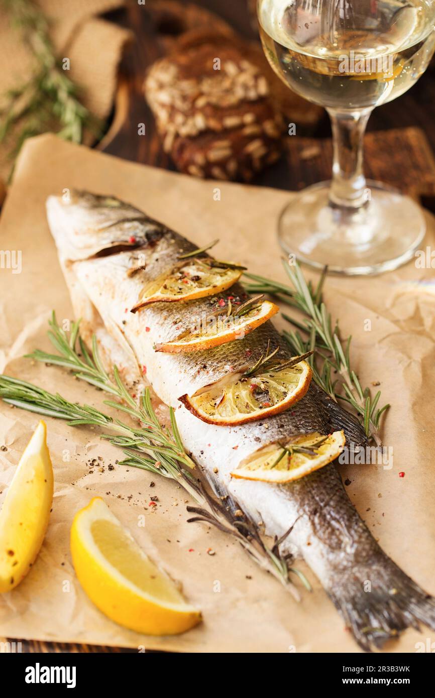 Oven-baked Sea bass with lemon and herbs. Seabass fish, baked entirely Stock Photo