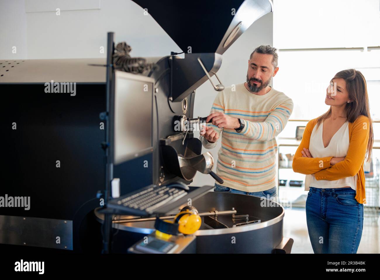 Man explaining coffee grinding process to woman at cafe Stock Photo