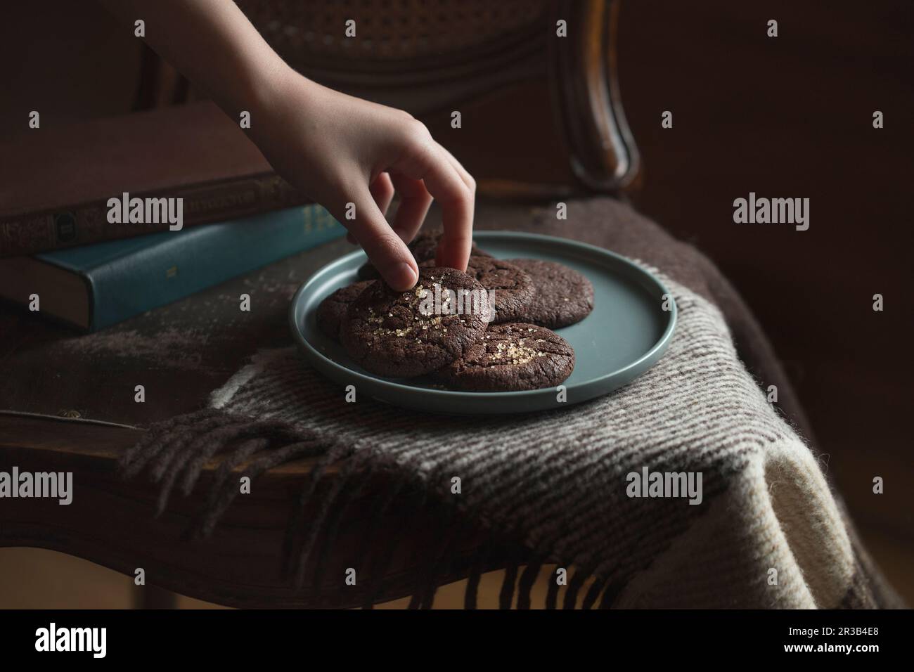 Chocolate cookies on the plate. Dark and Moody, Mystic Light food photography. Children's hand takes Stock Photo