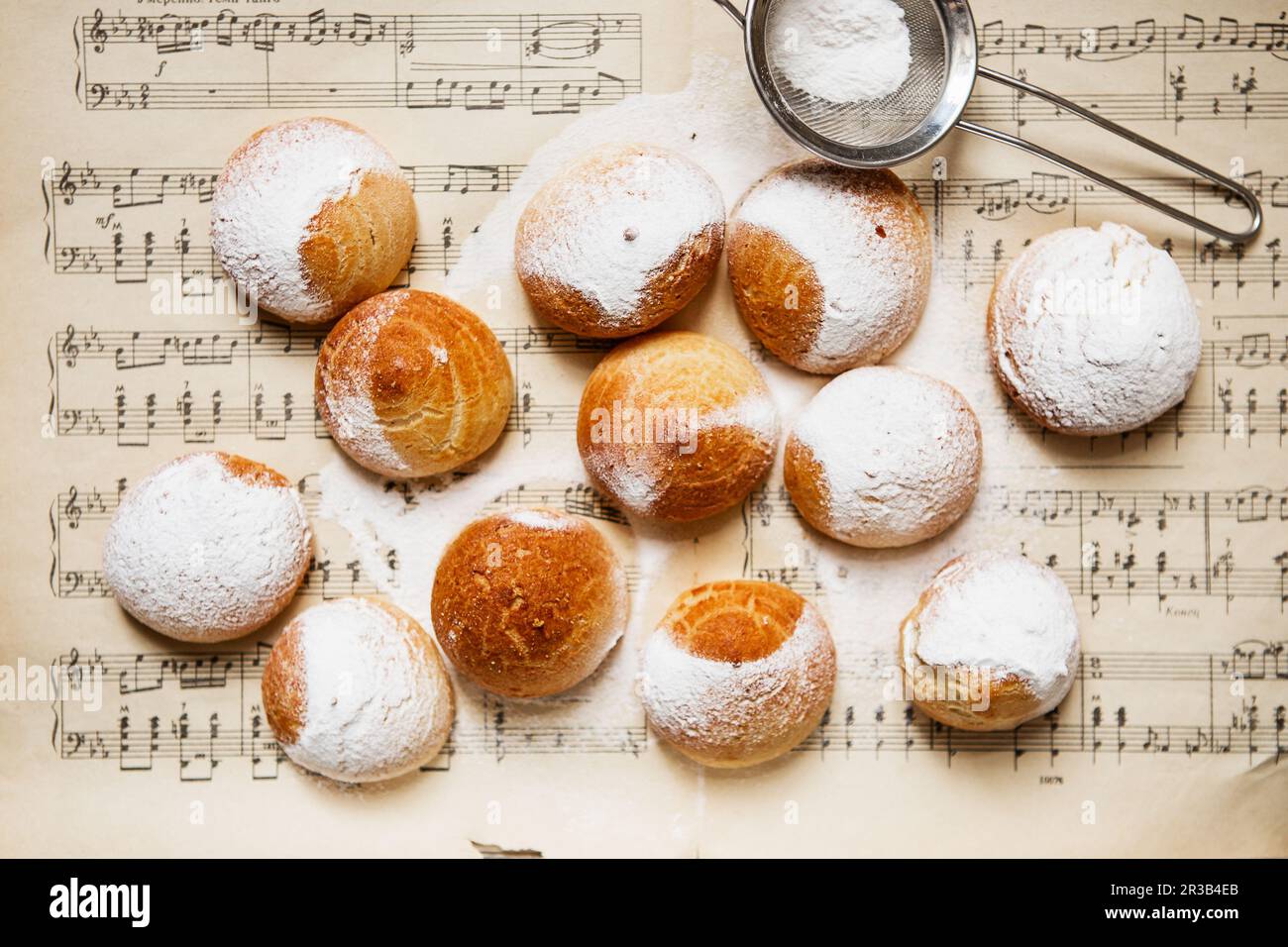 Homemade profiteroles on the music sheet with notes. Profiteroles (choux Ã  la crÃ¨me) - French choux Stock Photo