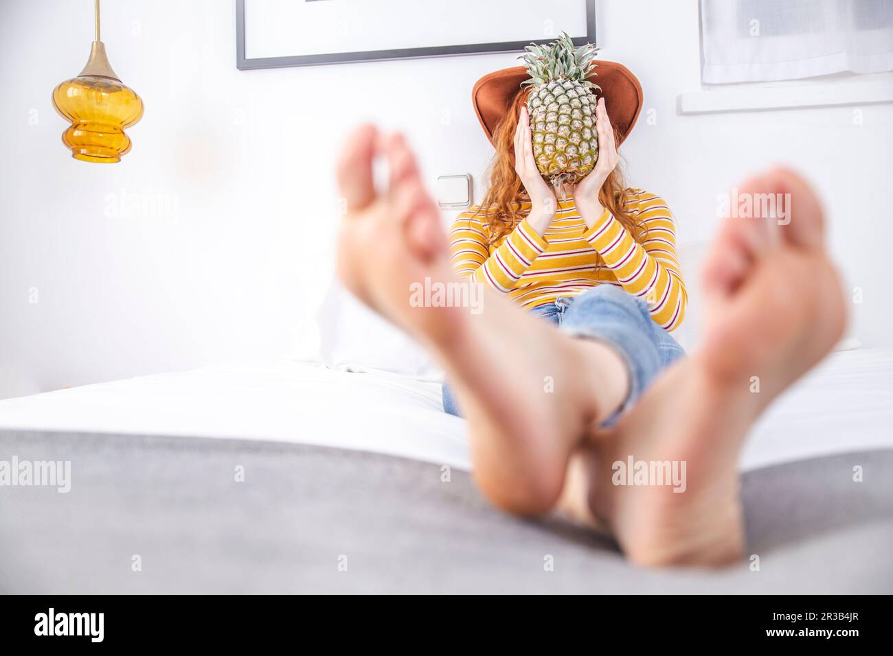 Woman holding pineapple in front of face on bed Stock Photo Alamy