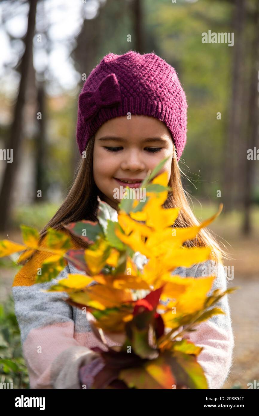 Cute girl wearing knit hat looking at leaves Stock Photo