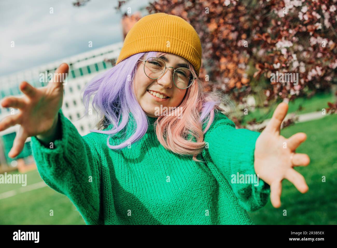 Smiling teenage girl with knit hat gesturing at park Stock Photo