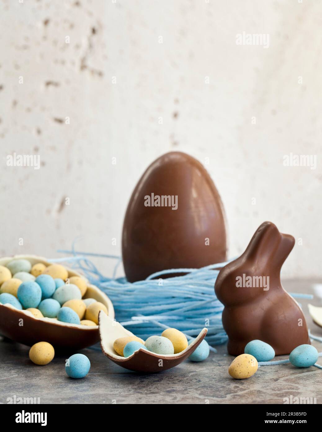 Easter chocolate egg in a blueberry candy nest, and a chocolate bunny, and a halved chocolate