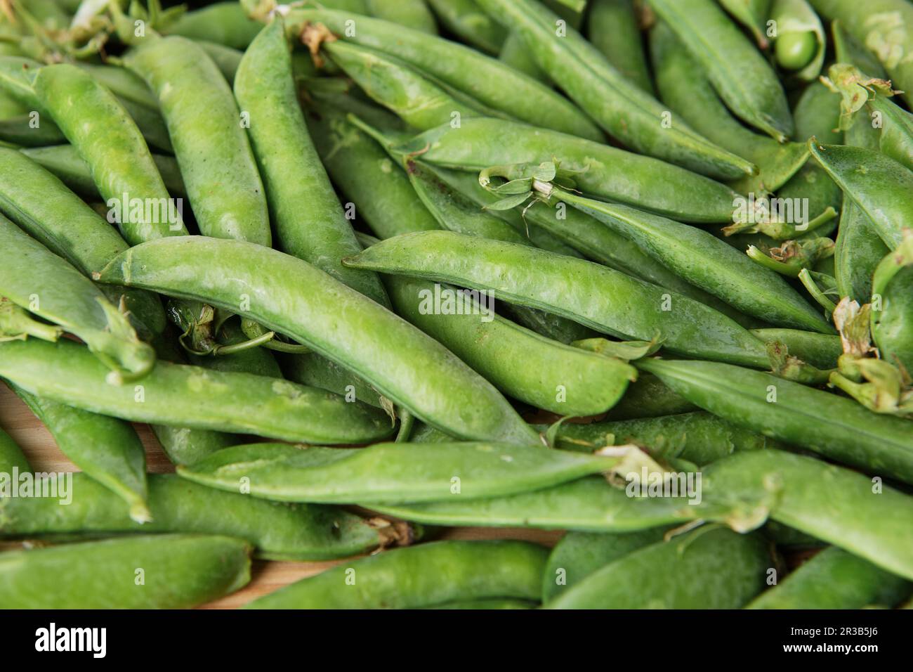 Green peas in pods freshly picked on wood. Some green peas. Fresh green peas. green pods with peas a Stock Photo