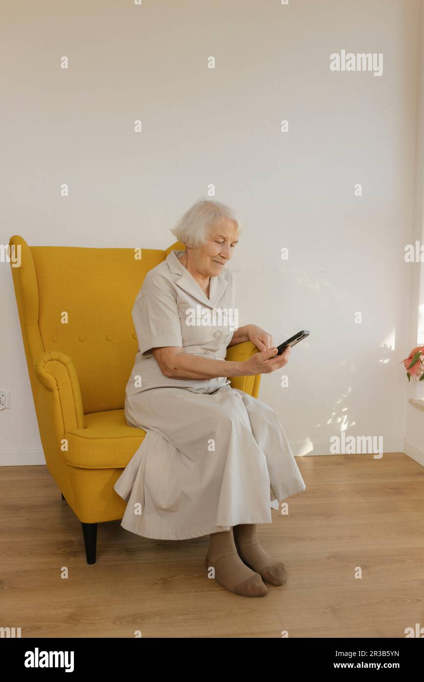 Elderly woman sitting in an armchair hi-res stock photography and ...