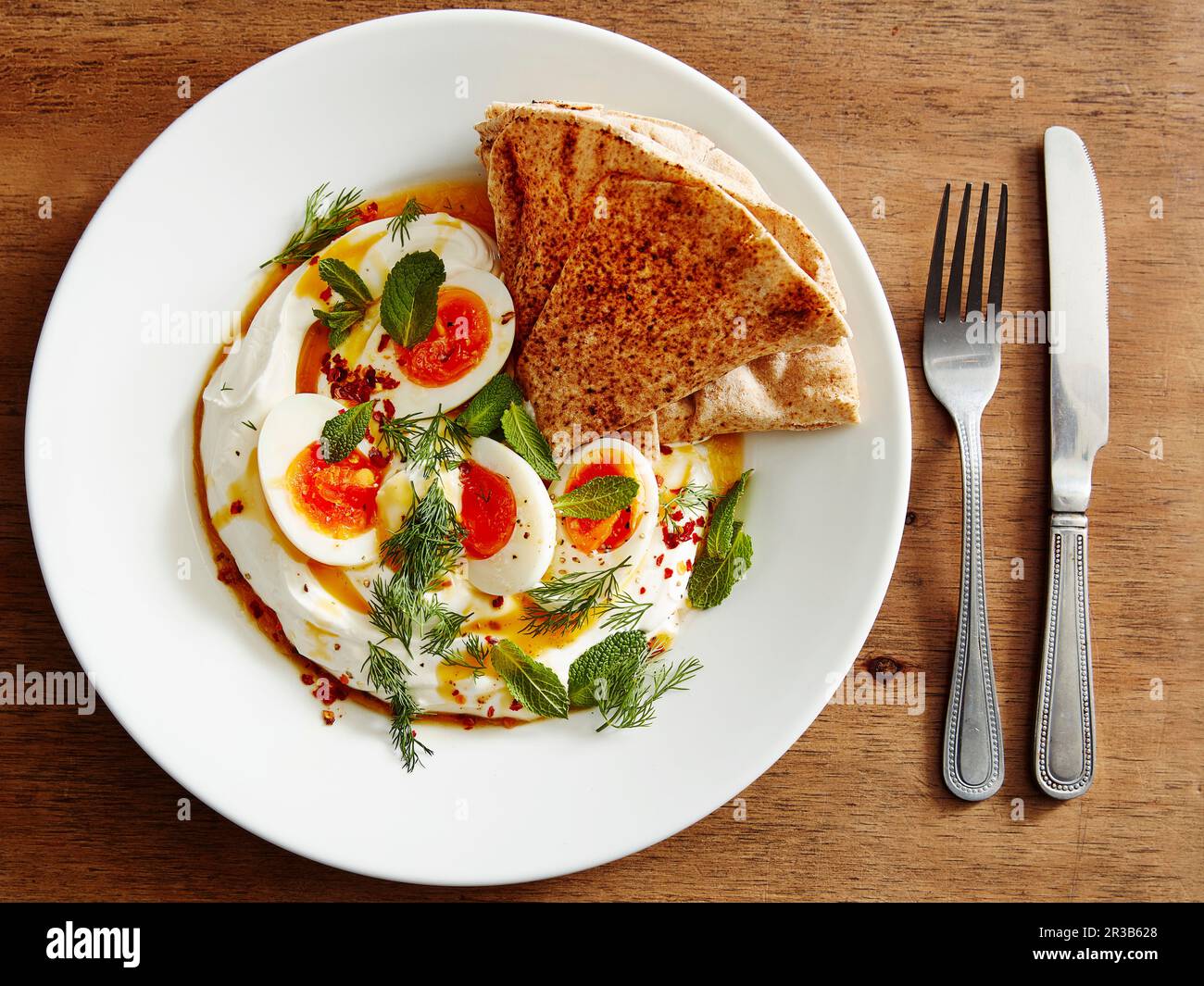Hummus with eggs, herbs and flatbread Stock Photo