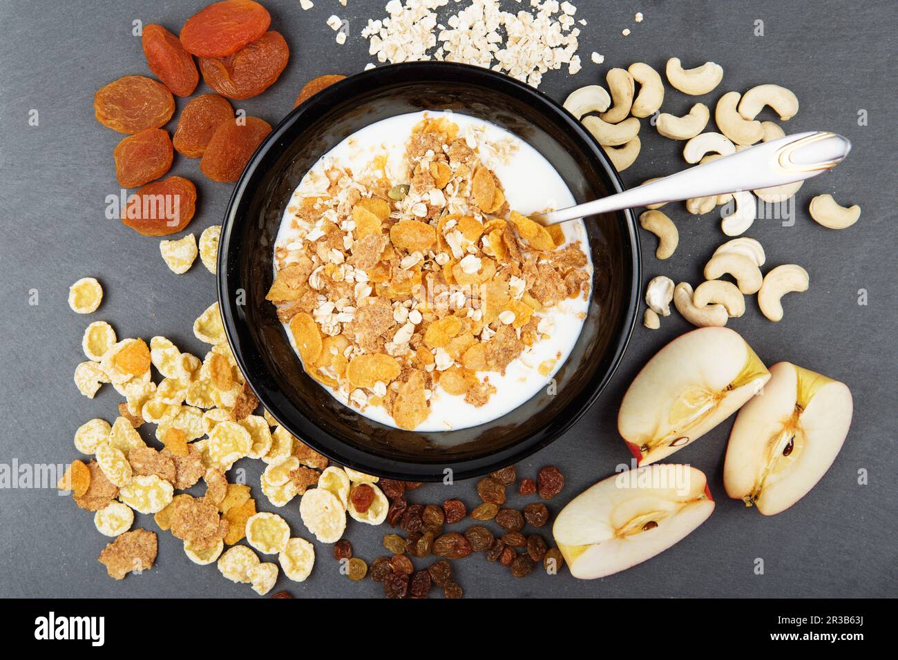 Muesli, nuts, fruits, milk and oatmeal for breakfast. Plate of oat flakes, cashew, apples and seeds Stock Photo
