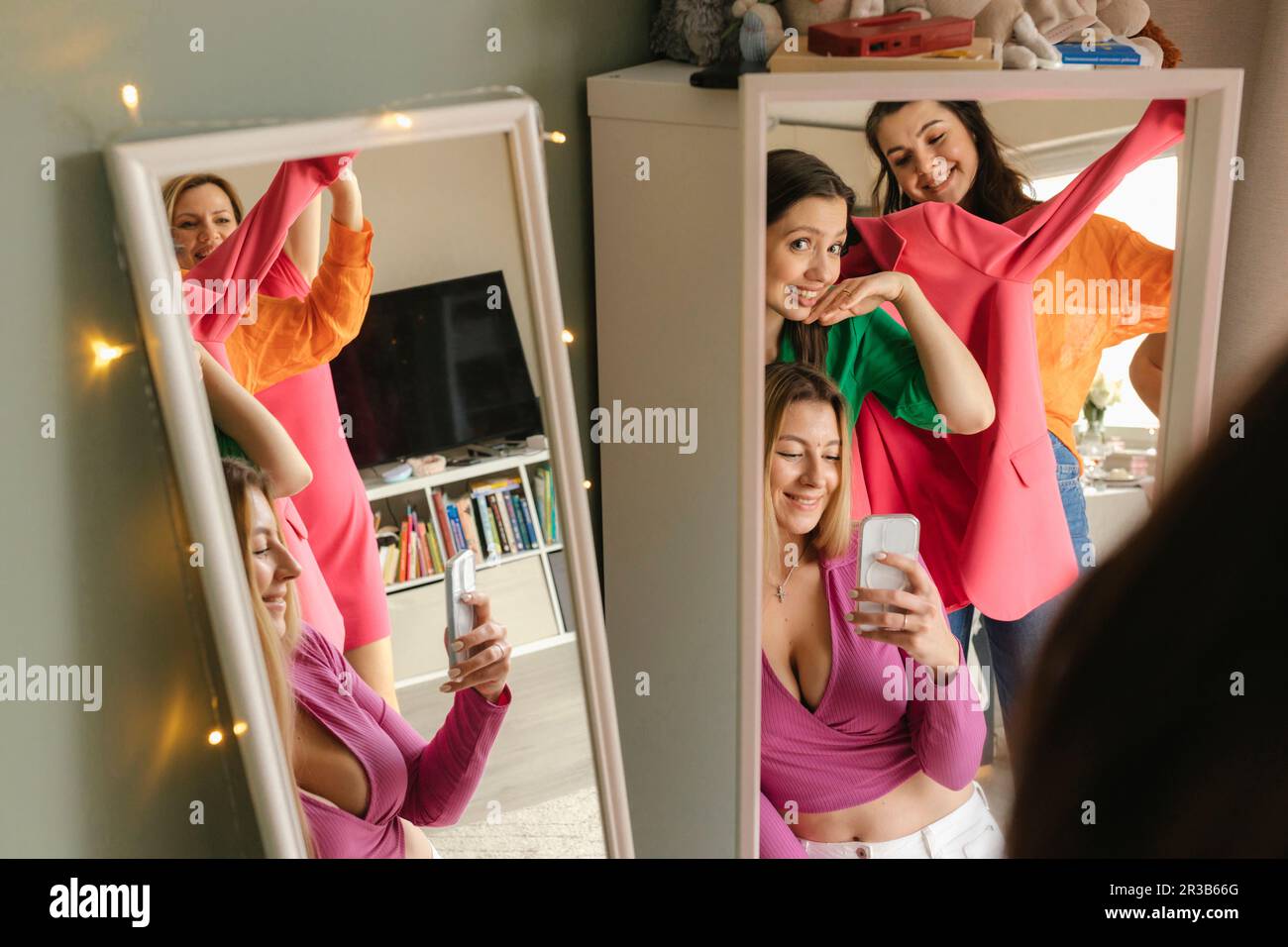 Woman taking mirror selfie with friends through mobile phone at home Stock  Photo - Alamy