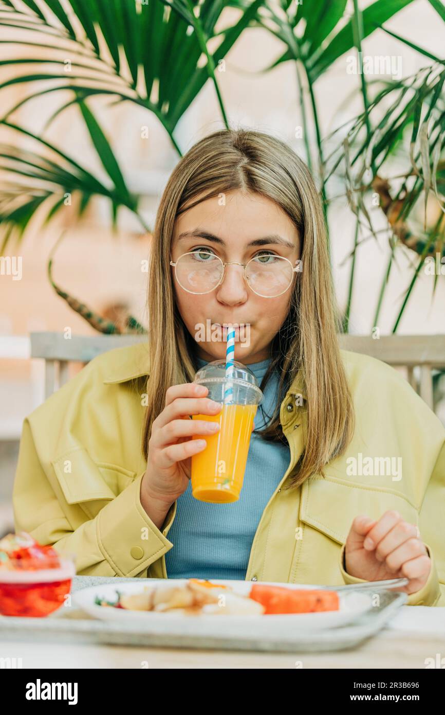 Teenage girl drinking juice sitting in school cafeteria Stock Photo Alamy
