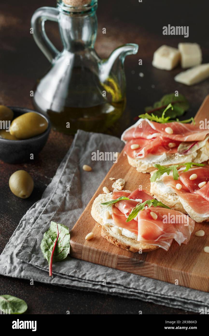 Traditional parma cured ham antipasto. Bruschetta set with Parma Ham and Parmesan Cheese. Small sand Stock Photo