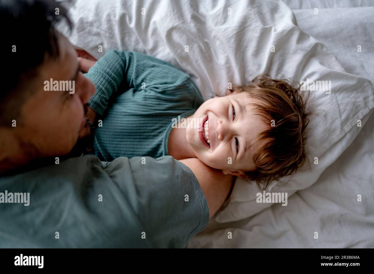 Father spending leisure time with son on bed at home Stock Photo