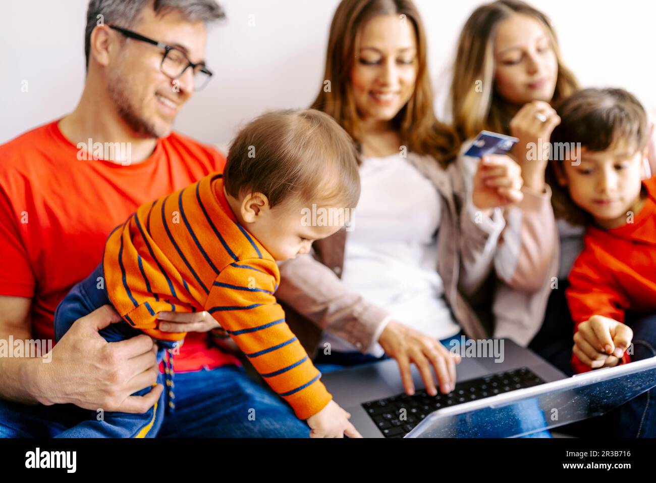 Family spending leisure time together with laptop at home Stock Photo