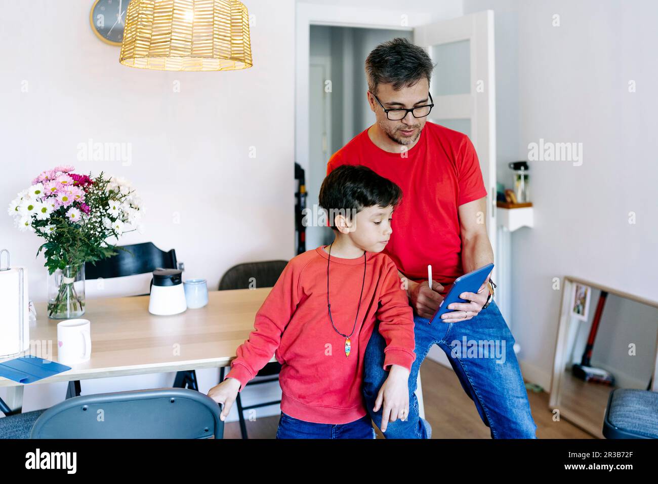 Son standing by father using tablet PC at home Stock Photo