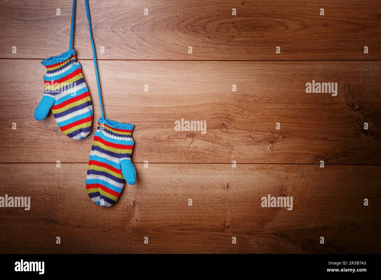Baby striped mittens on a wooden background texture Stock Photo