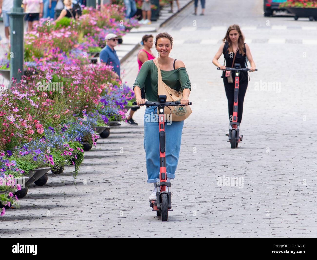 Two young women driving electric scooters at Karl Johan Street in Oslo, Norway. Stock Photo