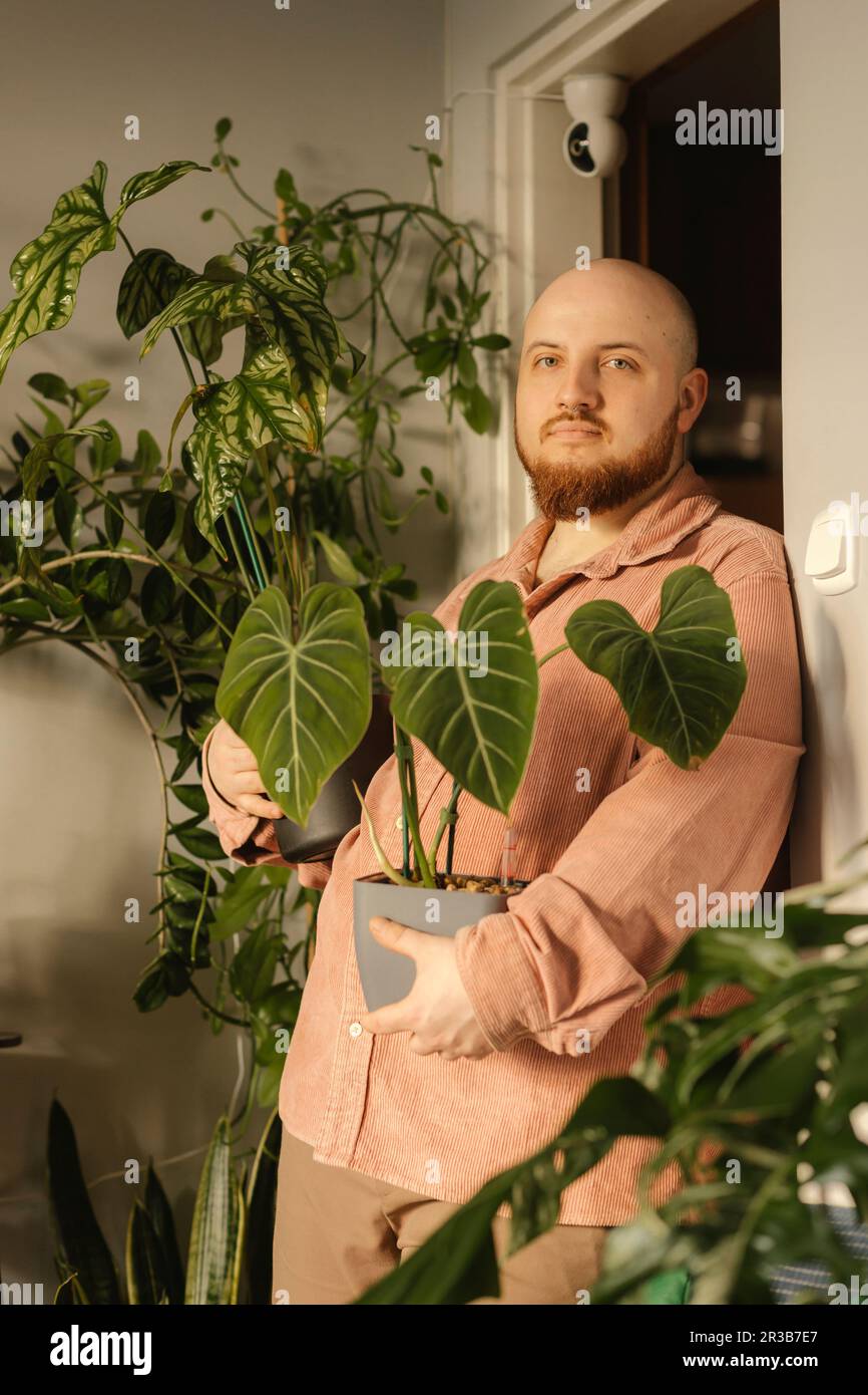 Man holding potted plants by door at home Stock Photo - Alamy