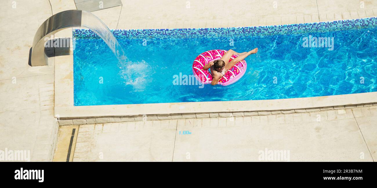 Happy kid playing in blue water of swimming pool on a tropical resort at the sea. Summer vacations c Stock Photo