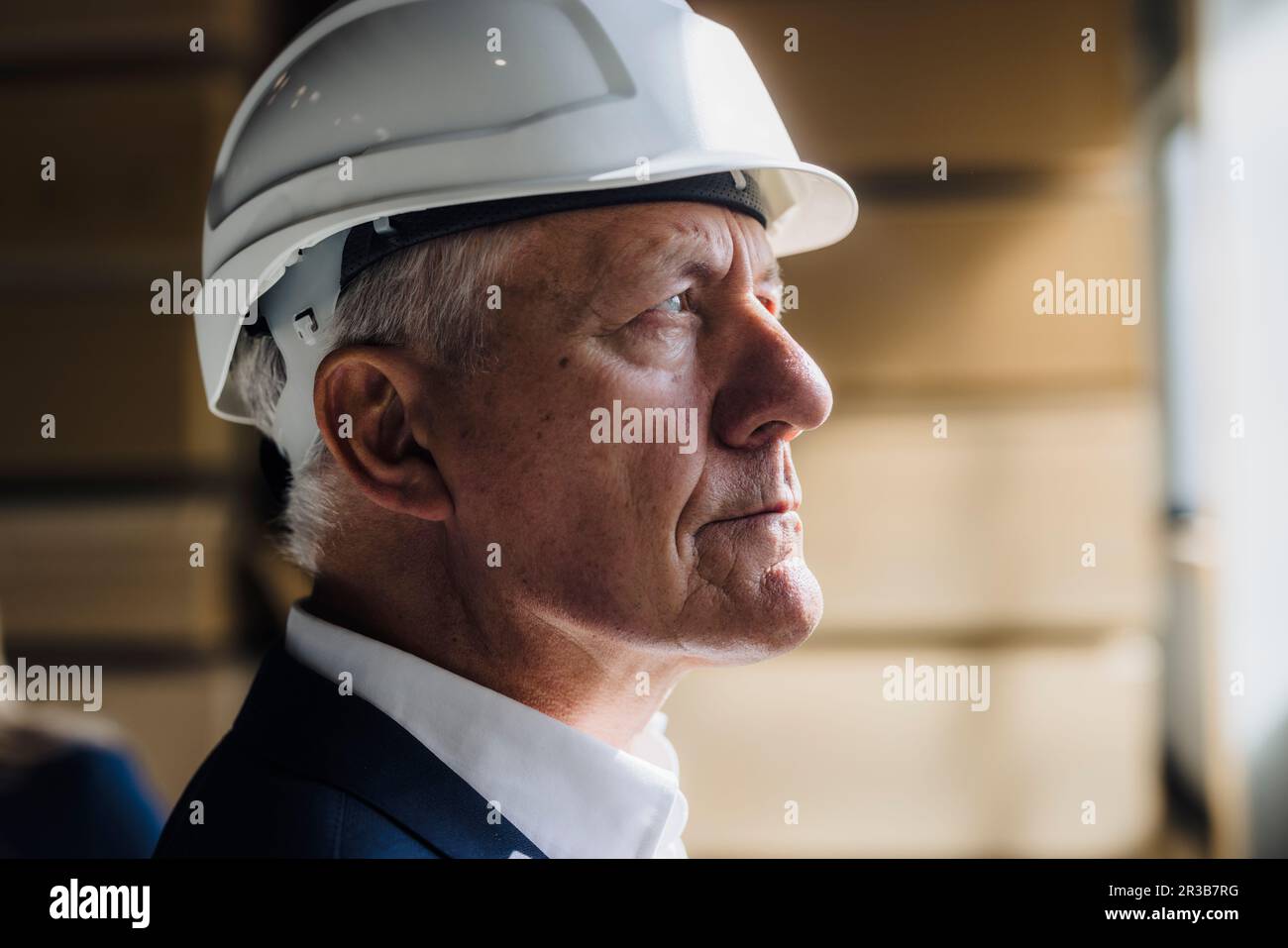 Contemplative senior businessman wearing hard hat in factory Stock Photo