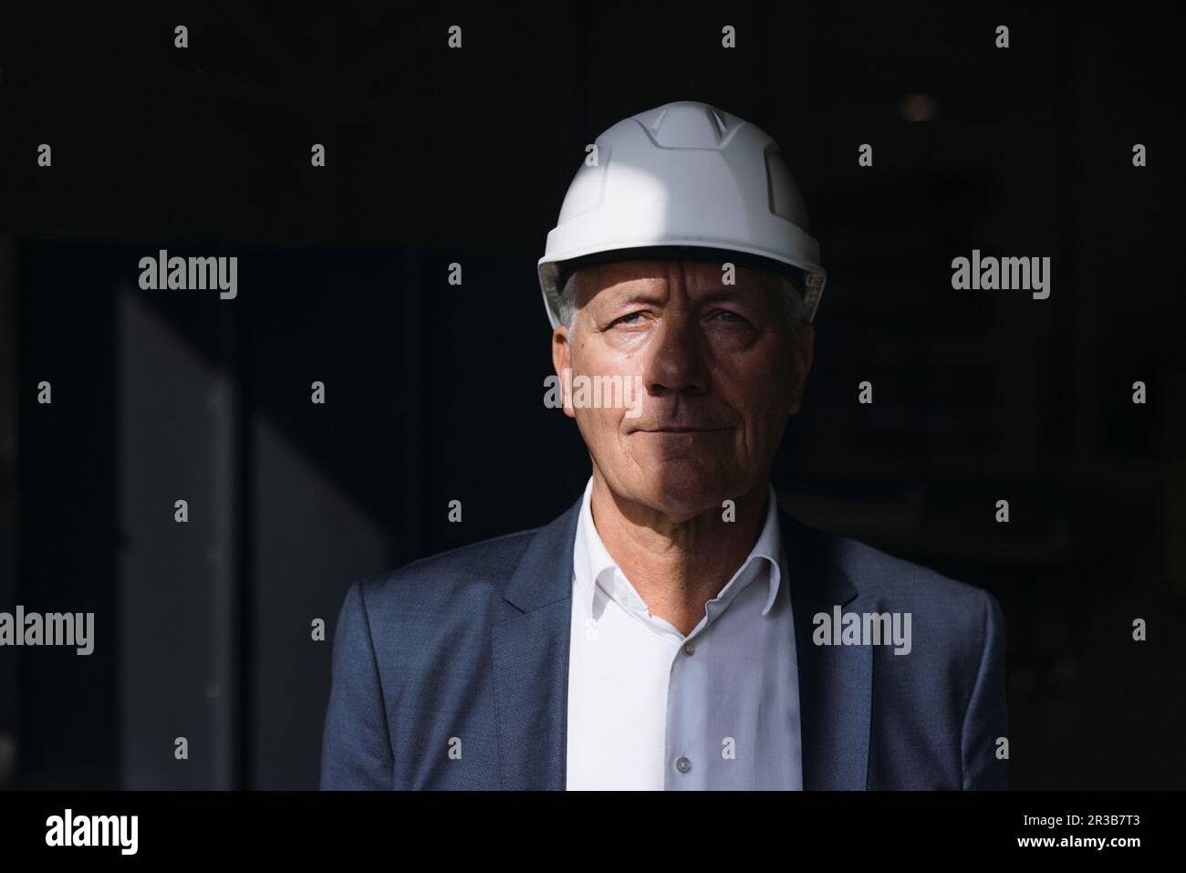 Businessman wearing blazer and hard hat in factory Stock Photo