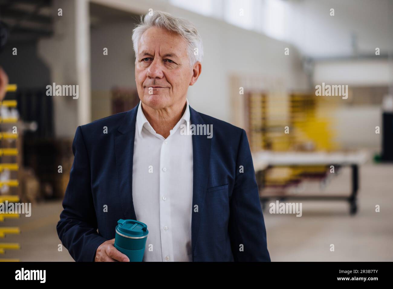 Thoughtful businessman holding water bottle in factory Stock Photo
