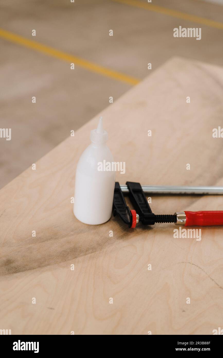 Glue bottle with clamp on wooden table in carpentry factory Stock Photo