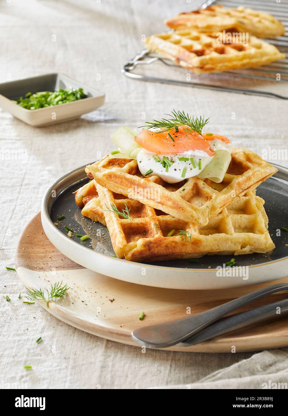 Potato waffles with salmon, sour cream, cucumber, dill and chives Stock Photo