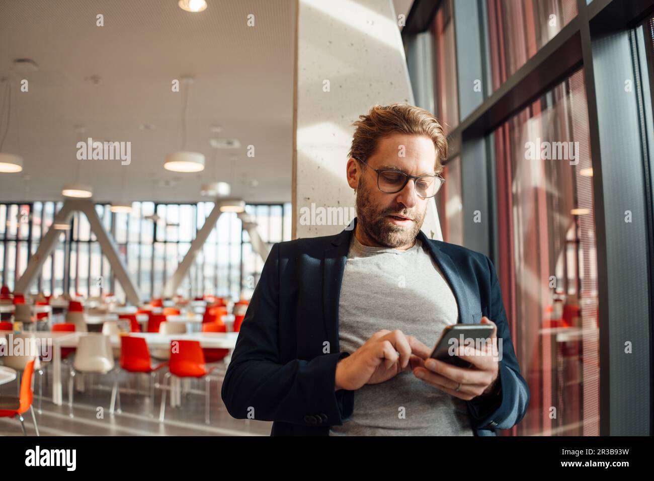 Businessman text messaging through smart phone at cafeteria Stock Photo