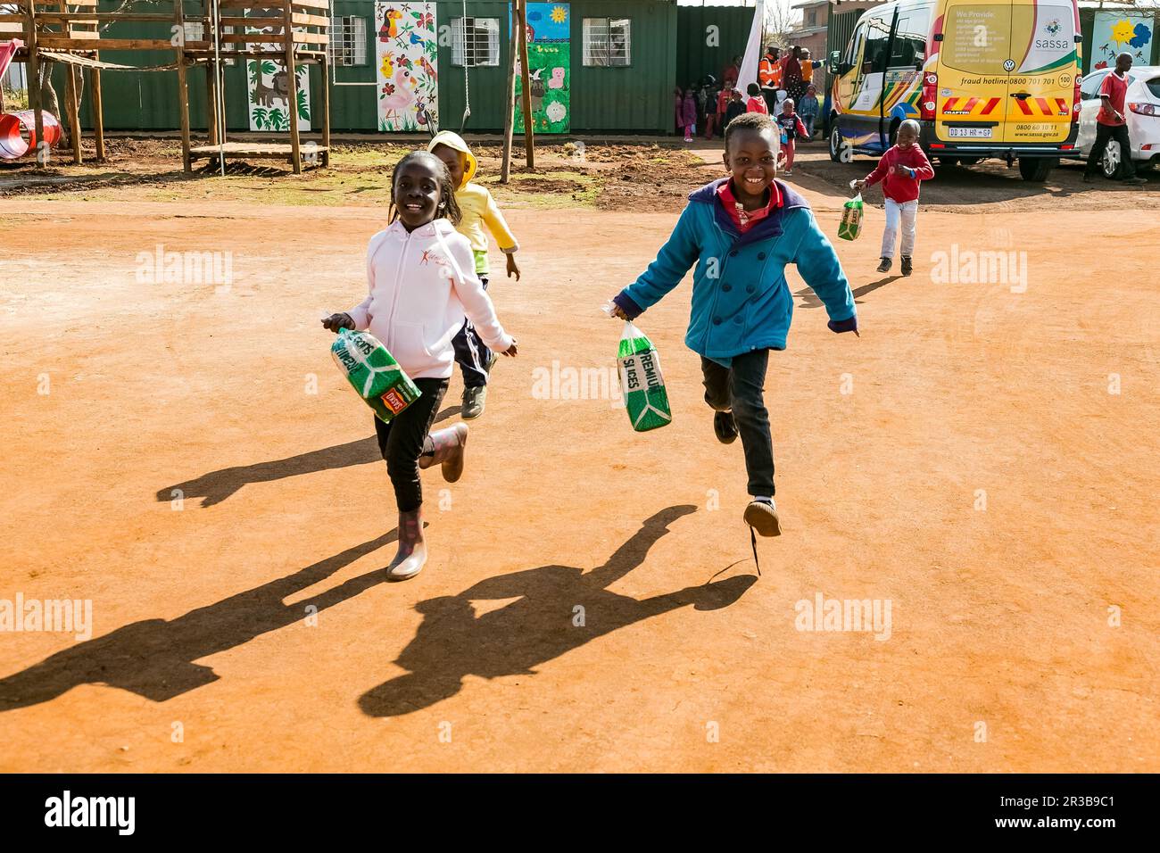 Young African Preschool kids running with a loaf of bread in the playground of a kindergarten school Stock Photo