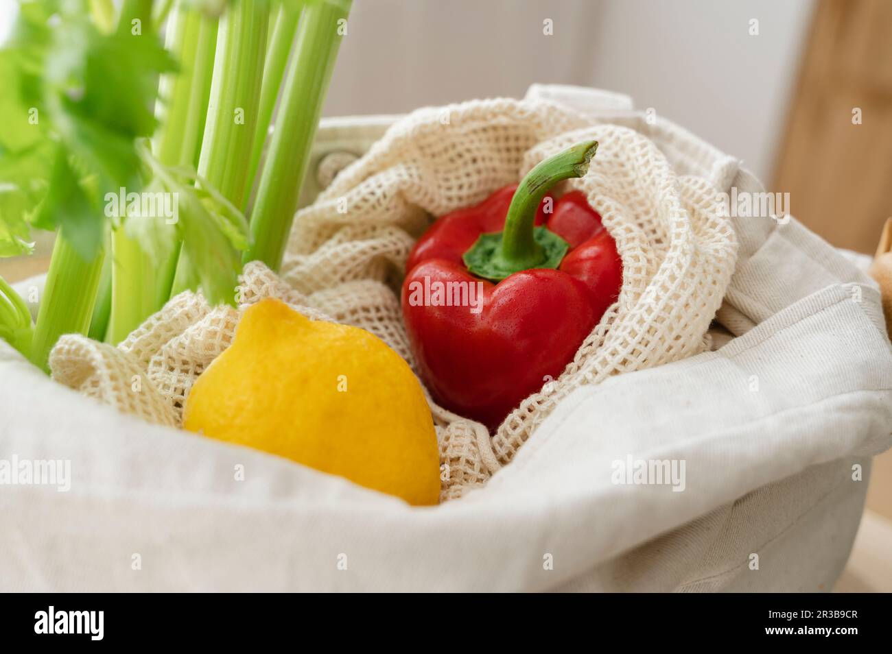 Fresh red bell pepper with lemon and celery in reusable bag at home Stock Photo