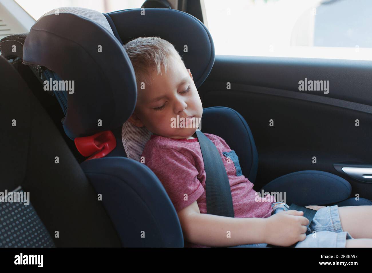 Boy sleeping on safety seat in car Stock Photo