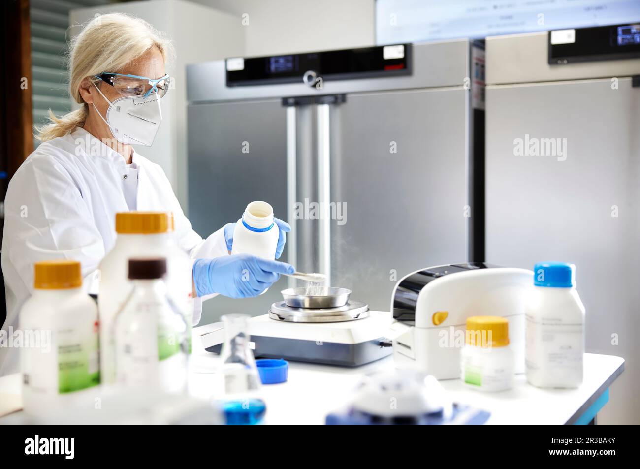 Scientist measuring chemical on weighing scale in laboratory Stock