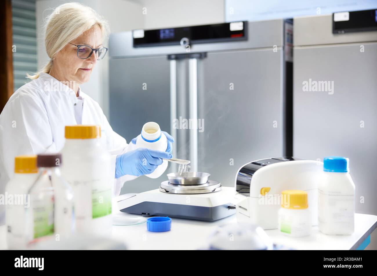 Scientist measuring chemical on weight scale in laboratory Stock Photo