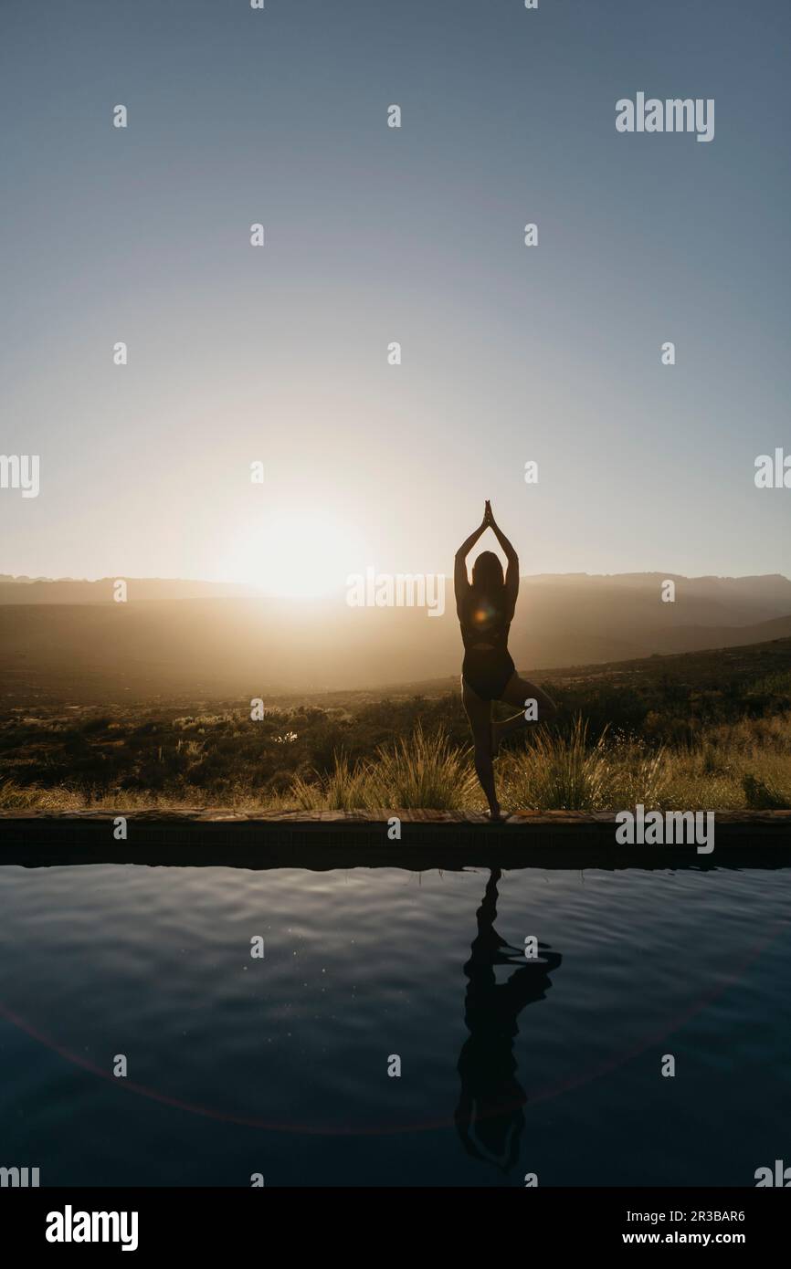Woman practicing tree pose at poolside Stock Photo - Alamy