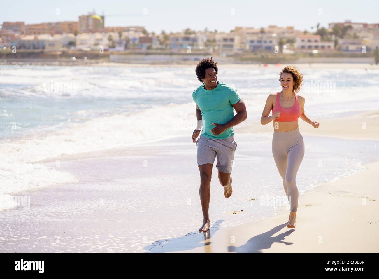Smiling couple jogging together at beach Stock Photo